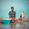 a man and a dog sitting on a beach